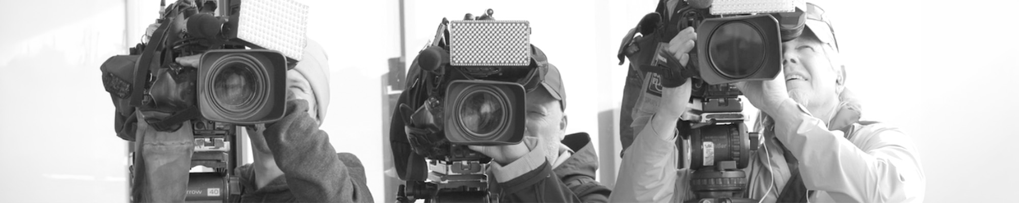 Three camera operators pointing cameras towards the viewer